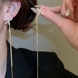 Boucles d'oreilles dorées en X avec de longs glands métalliques et des zircons