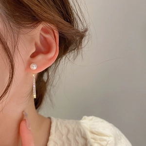 Close-up of elegant pearl earrings with sparkling micro-pave zircon drops on a female model
