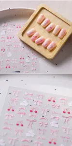 Detail of matte pink bow and cherry 3D nail stickers on natural wood background