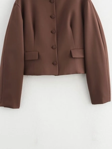 Detail of dark brown cropped blazer featuring matching buttons and textured fabric
