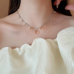 Gros plan d'un collier argenté avec perles de résine transparentes sur un mannequin