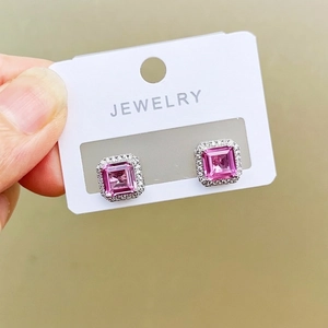 Macro view of pink square princess cut sapphire earrings with pavé set halo detailing