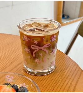 Gros plan d'un verre avec motifs floraux roses et café glacé avec glaçons à l'intérieur
