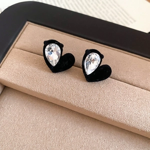 Macro detail of heart-shaped velvet earrings with crystal teardrop in a jewelry box