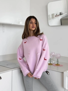 Detail of pink knitted sweater showing cute embroidered dachshund pattern and soft texture