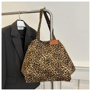Close-up of leopard print canvas tote bag featuring brown leather logo patch details