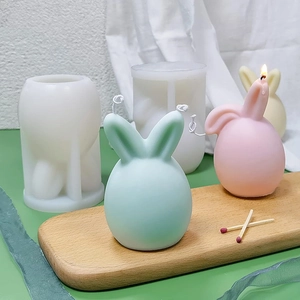 Detail of Easter bunny silicone molds and colorful rabbit scented candles on a wooden tray