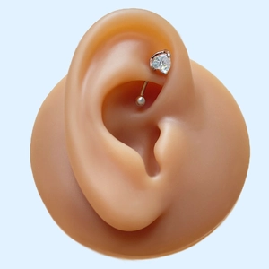 Detailed close-up of a silver curved barbell with a heart-shaped zircon on a silicone ear model