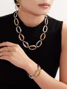 Detail of mixed gold and silver oval chain jewelry set worn by a model in black