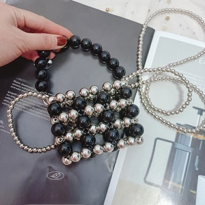Detail of handmade beaded mini bag with silver and black beads on a magazine backdrop