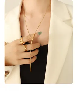 Detailed view of an 18K gold plated Y-necklace and stackable rings on a female model