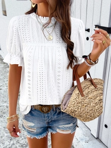Close-up detail of white short-sleeve top featuring intricate hollow embroidery patterns