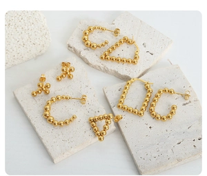 Detailed macro view of assorted 18k gold plated U-shaped bead earrings on a white stone base