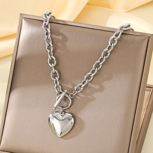 Detailed close-up of a silver heart pendant necklace with OT toggle clasp on silk