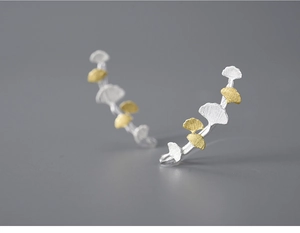 Detailed macro shot of ginkgo leaf earrings with a two-tone gold and silver matte texture