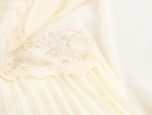 Dettaglio del delicato pizzo crema e dell'elegante texture del tessuto in chiffon a pieghe