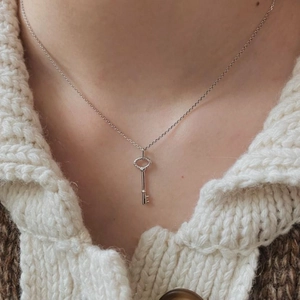 Minimalist 925 sterling silver key pendant necklace worn on white knit sweater