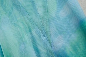 Detailed macro shot of blue-green gradient pleated mesh fabric with fine net texture