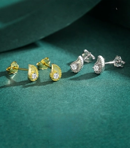 Close-up of gold and silver S925 sterling silver teardrop studs with white round stones
