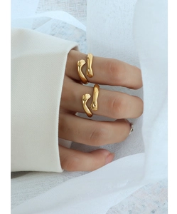Detailed close-up of golden hugging hands rings worn on fingers with white fabric background