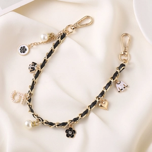 Detail of luxury gold metal chain interwoven with black leather and camellia charms