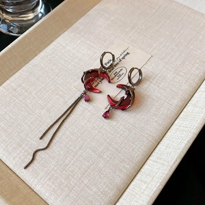 Detail view of asymmetric vintage earrings with red gemstones in a jewelry box