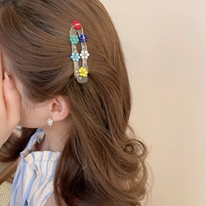 Detail view of colorful beaded flower hair clip styled on a woman's brown wavy hair