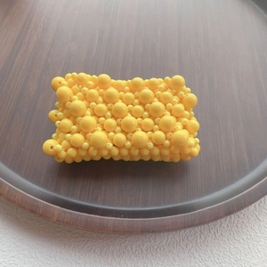 Detailed top view of a handmade yellow beaded pouch on a rustic dark wooden tray
