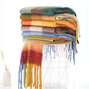 Detail of soft rainbow plaid scarves with fringe stacked in a minimalist white metal basket