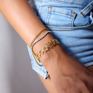 Makroaufnahme von mehrlagigen Goldarmbändern mit Sternen-Design und Tennis-Armband-Stil