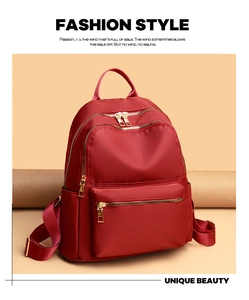 Close-up of burgundy oxford cloth backpack with multiple compartments and gold zippers
