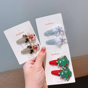 Hand holding Christmas hair clips with glitter reindeer, snowflakes, and festive trees