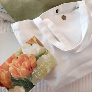 Detail of white canvas tote bag with metal snap button closure and thick textured fabric