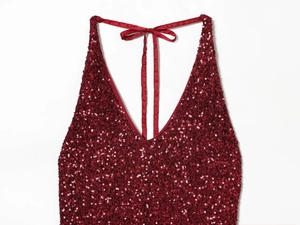 Detail of burgundy sequin dress showing deep V-neckline and satin halter neck bow