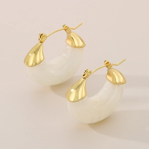 Detail view of U-shaped gold earrings with beige marbled resin in a crescent design