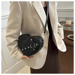 Détail du sac bandoulière en forme de cœur avec clous argentés sur cuir noir