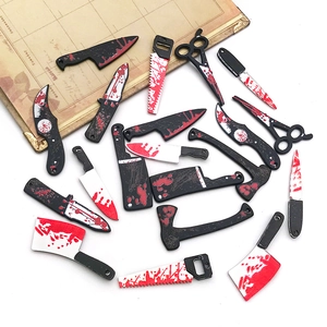 Detailed flat lay of miniature acrylic Halloween knife charms with red paint splatter