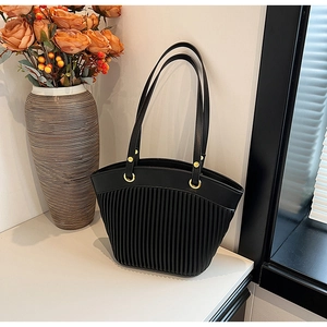 Close-up of black pleated tote bag showing unique vertical stripe texture and gold hardware