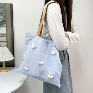Detail of blue gingham tote bag with five cute 3D plush ducks and khaki shoulder strap