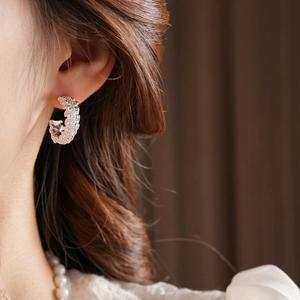 Close-up of silver C-shaped earrings with irregular texture on a model's ear