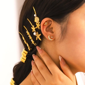 Golden starfish and shell hair clips with moon and star earring set on a model