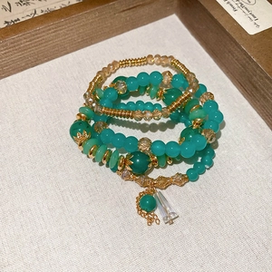 Detail of multi-layer beaded bracelet set with emerald green crystals and gold charms