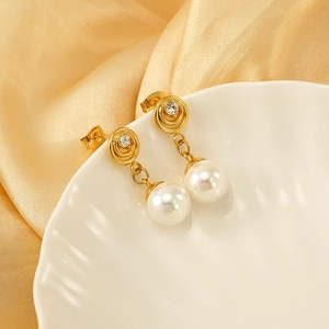 Detailed shot of a gold stud earring with clear crystal and white pearl on satin
