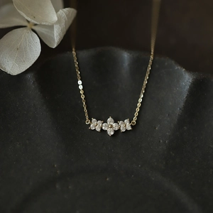Macro detail of gold S925 silver necklace with three sparkling clover flower pendants