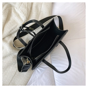 Internal view of black faux leather tote bag showing large main compartment and zip pocket