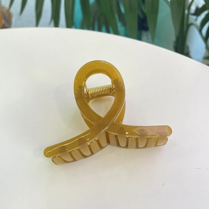 Détail macro d'une pince à cheveux en acrylique ambre avec ressort en métal doré