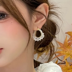 Detailed close-up of vintage style pearl hoop earrings on model with autumn maple leaves