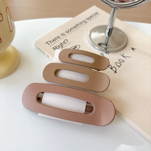 Detailed view of three matte brown hair clips in different sizes on a white card display