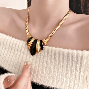 Detail of vintage French gold chunky chain necklace with black enamel pendant on model