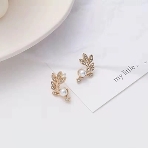 Detailed view of leaf-shaped gold stud earring with pearl and cubic zirconia accents